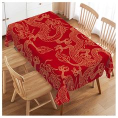 a red table cloth with gold dragon designs on it and two chairs in the background