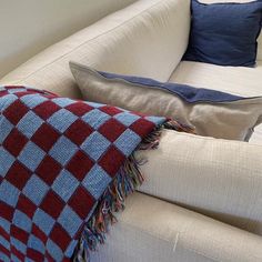 a red and white checkered blanket sitting on top of a couch next to pillows