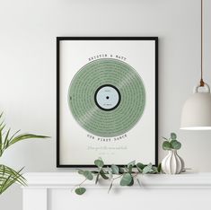 a white fireplace with a framed record on the mantle and potted plant next to it