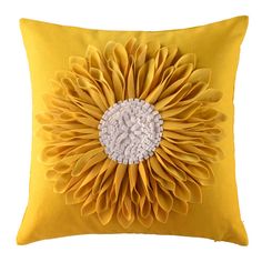 a yellow pillow with a large flower on the front and center, sitting on a white background