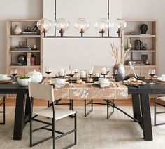 a dining room table is set with plates and glasses, candles, and bookshelves