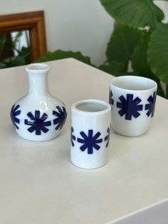 three white and blue vases sitting on top of a table