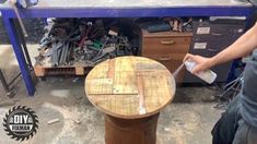 a man is using a brush to clean a wooden table in a garage with lots of tools