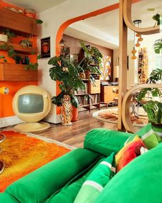 a living room filled with lots of green furniture and plants on top of the couches