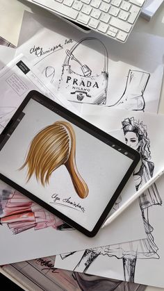 a tablet computer sitting on top of a desk covered in drawings and paper with a drawing of a woman's hair