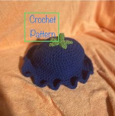 a crocheted blue hat with a green leaf on it sitting on a bed