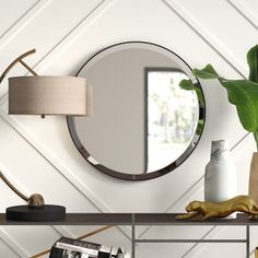 a table with a mirror, lamp and vase on it in front of a white wall