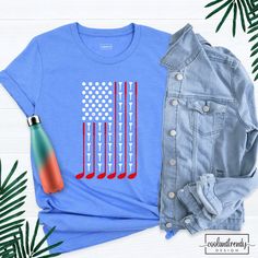 a blue shirt with an american flag on it next to a denim jacket and palm leaves