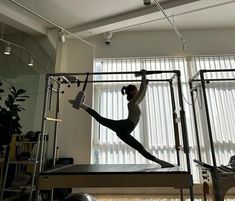 a woman is doing exercises on a pivot machine in the middle of a room