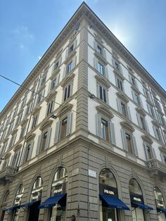 a tall building with many windows and blue umbrellas