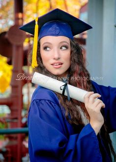 a young woman wearing a graduation cap and gown holding a diploma in front of her face