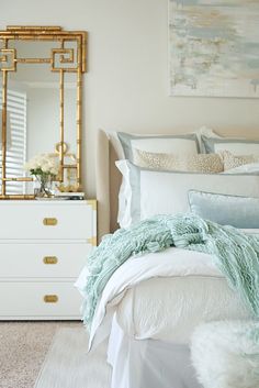 a bedroom with white bedding and gold accents