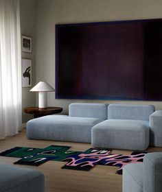 a living room with blue couches and rugs on the floor next to a large painting