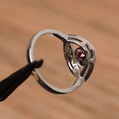 It is a natural garnet ring. The main stone is 5mm*5mm round cut, weight about 0.67 carats. The basic metal is sterling silver and plated with rhodium. To change the metal to a solid gold (white/rose) or platinum is also available, please ask for a quotation if you want. You can also go to my shop Home for more elegant rings: https://www.etsy.com/shop/godjewelry?ref=hdr_shop_menu More garnet rings: https://www.etsy.com/shop/godjewelry?ref=seller-platform-mcnav&section_id=20709242 Customizati Elegant Garnet Crystal Round Ring, Silver Garnet Ruby Ring With Center Stone, Silver Garnet Round Jewelry, Red Sterling Silver Crystal Ring With Gemstone, Silver Ruby Ring With Hallmark, Round Cut, January Birthstone Rings, Red Garnet Ring, Garnet Engagement Ring, Round Halo Engagement Rings