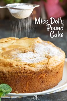 a cake is being sprinkled with powdered sugar on a plate next to mint leaves