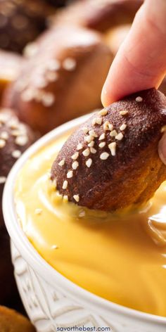 a person dipping some kind of doughnut with mustard