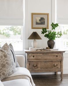 a living room scene with focus on the chest of drawers and plants in vases