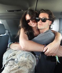 a man and woman are sitting in the back of a car, hugging each other