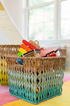 two wicker baskets filled with toys sit on a colorful rug in front of a staircase