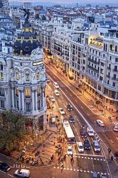 an aerial view of a city street with traffic and buildings in the background at dusk