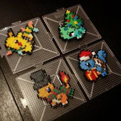 four pieces of perler bead art sitting on top of a table