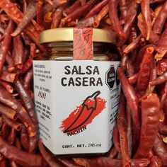 a jar of salsa casera sitting on top of some red chili peppers in a pile