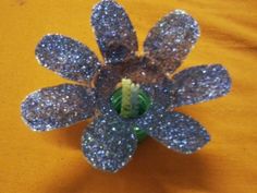 a silver flower brooch sitting on top of a yellow cloth