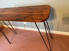 a wooden table with hairpint legs on the floor in front of a wall