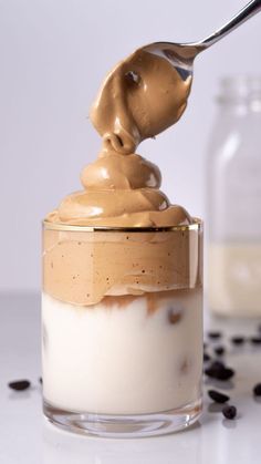 a spoon with some food in it on top of a glass jar filled with pudding