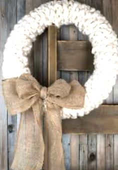 a white wreath with a bow hanging on a wooden door