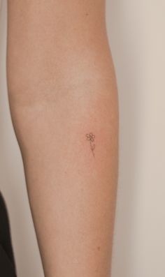 a person with a small flower tattoo on their left arm and the back of her leg