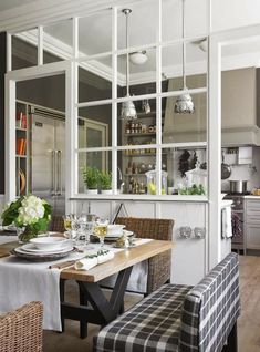 a dining room table set with place settings and chairs, in front of the kitchen