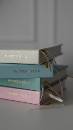 a stack of four books sitting next to each other on top of a white table