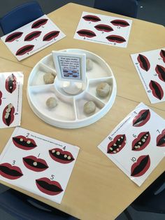 a wooden table topped with lots of cards and magnets covered in red lipstick shapes