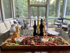 a wooden tray filled with wine bottles and assorted food on top of a table