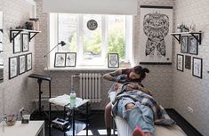 a woman laying on top of a bed in a room with pictures on the wall