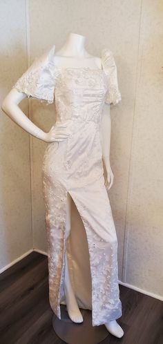 a mannequin dressed in a white dress with an open back and high slit