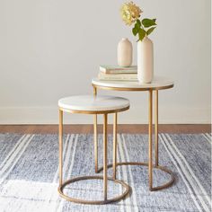 two tables with white marble tops and gold metal legs, one has a flower vase on top