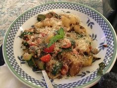 a white and blue plate topped with pasta and veggies covered in parmesan cheese