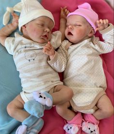 two babies laying next to each other on top of a pink blanket with stuffed animals