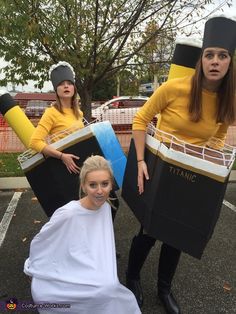 two women dressed in costumes standing next to each other with their hair pulled back and one woman sitting on the ground