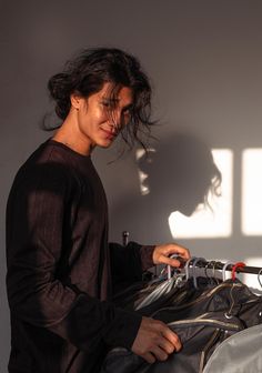 a man standing next to a wall with a bag on top of it and his shadow cast on the wall behind him