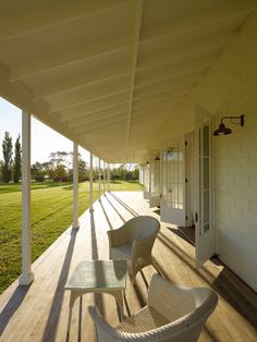 two wicker chairs sitting on top of a wooden porch next to a white building