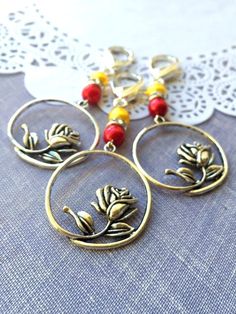 three hoop earrings with flowers and beads hanging from the ends on a lace doily