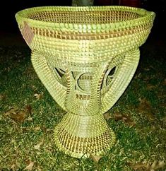 a wicker basket sitting on the ground in front of a tree and grass area