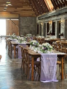 tables and chairs are set up in the middle of an empty room with purple linens on them