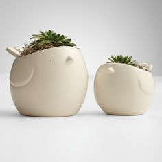 two white ceramic planters with plants in the shape of animals, one shaped like an elephant