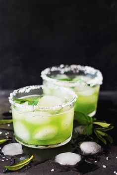 two glasses filled with ice and green drinks