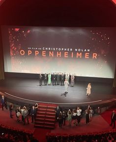 a group of people standing on top of a stage in front of a large screen