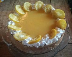 a pie with lemons and whipped cream on top is sitting on a wooden table